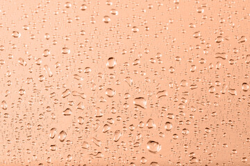 Metallic foil texture with water drops in trendy color 2024 Peach Fuzz as background