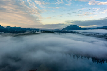 Valley by Lake, Mountains and Green Trees covered in fog. Canadian Landscape Nature Aerial Background