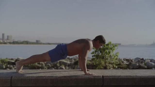 Homem jovem praticando atividades fisicas ao ar livre em frente ao mar. Cinematico 4k.