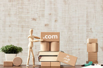 There is wood cube with the word .com or. It is as an eye-catching image. - Powered by Adobe