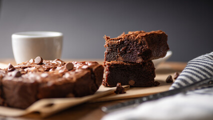 Chocolate chip brownies with coffee and chocolate chips with fork and knife on a wooden board and...