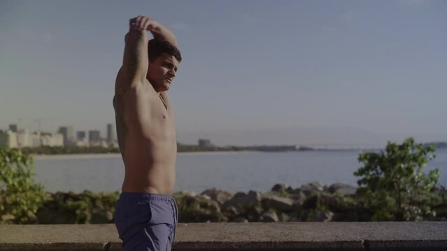 Homem jovem se alongando ao ar livre em frente ao mar. Cinematico 4k.