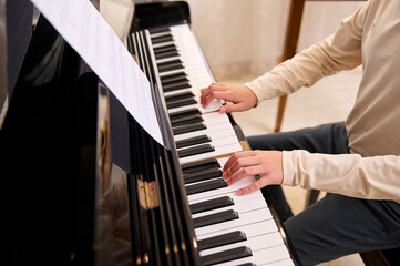 Close-up view from above of a child boy playing grand piano. Lesson of music.