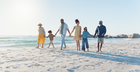 Holding hands, walking and big family at the beach on vacation, adventure or holiday together. Love, travel and children with parents and grandparents on the sand by the ocean or sea on weekend trip.