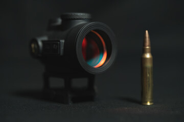Red dot sight for firearms and 5.56x45mm, cartridge, close-up photo.