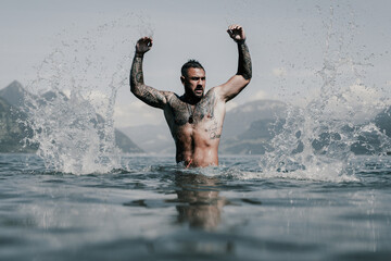 Naked muscular Hispanic man splashing water in lake. Attractive male sexy model in water. Handsome boy rest in Alps lake water. Sexy man naked torso in water. Man freedom lifestyle. Strong muscles guy - Powered by Adobe