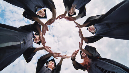 College graduates make a circle of their hands. - obrazy, fototapety, plakaty