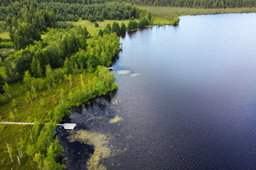 An overhead perspective reveals a rustic pier reaching into the calm, reflective waters of a lake,...