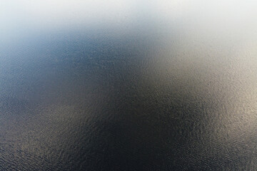Aerial Expanse of Rippling Waters. The vastness of a serene lake is captured in this aerial photo, with gentle ripples on the water's surface creating a mesmerizing texture that invites contemplation