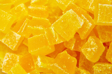Diced mango dried fruits texture background, top view. Dehydrated mango chips dices, sweet food closeup. The sweet aroma of dehydrated mango cubes is irresistible