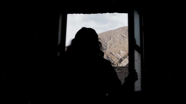 Woman Opening a Window in Dark Room in Iruya, Salta Province, Argentina. 4K Resolution.
