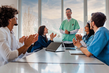 A medical team of doctors supports with applause in celebration at the meeting in the office...