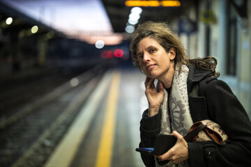 Handsome Woman Traveler Waiting for a Train on the Platform of a Railway Station in Italy in the Early Morning