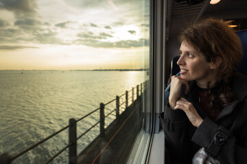 Curious Caucasian Woman Enjoying the View From Her Seat on a Public Train Transportation