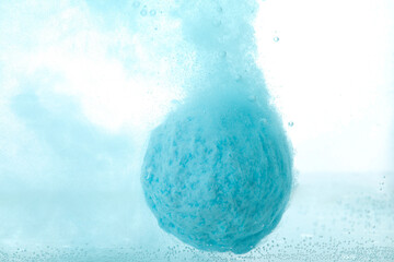 Light blue bath bomb dissolving in water, closeup