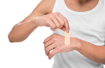 Man putting sticking plaster onto hand on white background, closeup