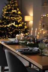 Christmas table setting with festive decor and dishware in room