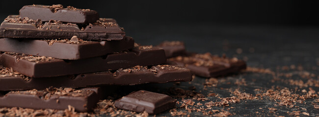 Tasty chocolate and shavings on dark table, closeup. Banner design with space for text