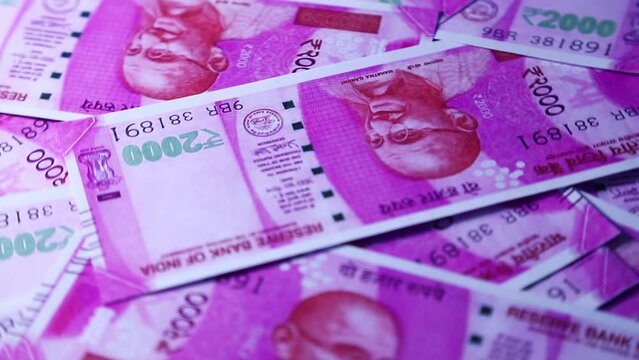 Camera panning 360 degrees around spread 2000 Indian rupee notes. Camera moving around Scattered rupee notes on surface