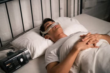 Foto op Plexiglas Asian man wearing cpap machine sleeping smoothly all night in bedroom.  © Kawee