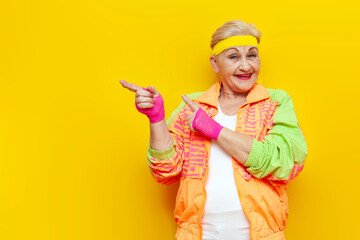 funny old granny in sports hipster clothes pointing at copy space on yellow isolated background,...