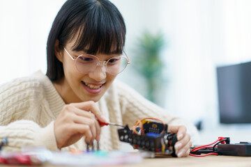 Woman assemble a robot and coding.