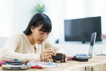 Woman assemble a robot and coding.