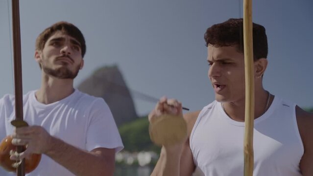 Jovens tocando instrumentos musicais tipicos brasileiros. Jogando capoeira, arte marcial afro-brasileira, no Rio de Janeiro. Cinematico 4k.