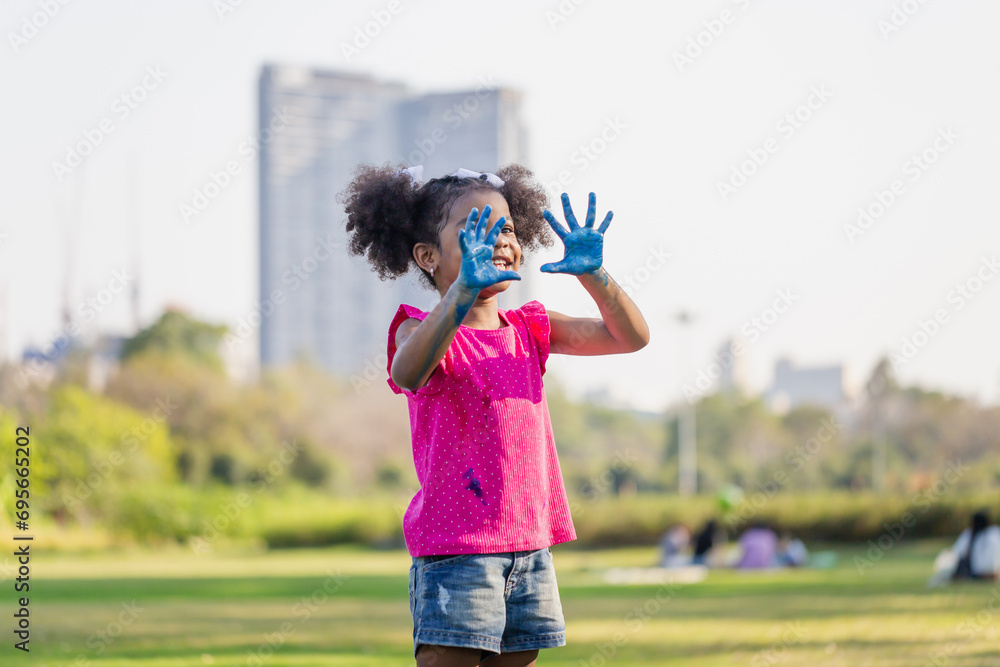 Wall mural Cheerful little child girl showing painted hand, Cute little kid girl playing outdoors in the garden