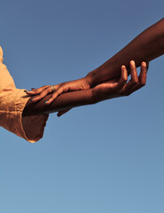 Black couple holding hands against blue sky