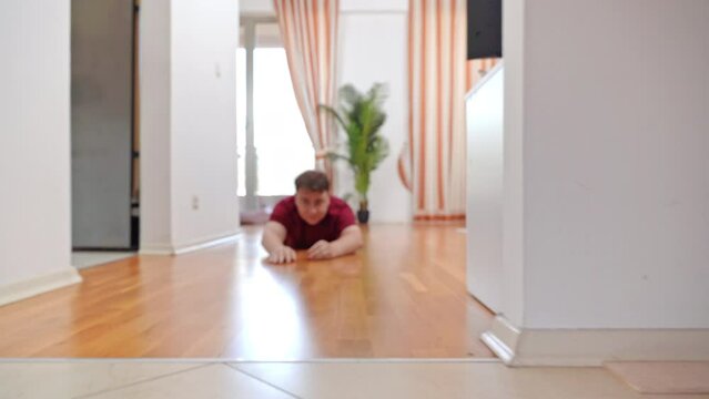 Man screams with emotion, stretches out his arms in front of him, holds them in death grip, slides along a flat surface of floor, pulls him forward man is dragged along laminate on stomach, challenge