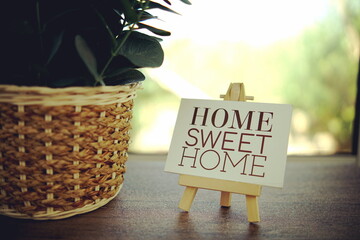 Home Sweet Home text message on paper card with wooden easel on wooden table background
