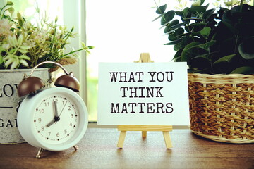 What you think matters text message on paper card with wooden easel, business concept background