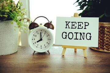 Keep going text message on paper card with wooden easel on wooden table background, inspiration...