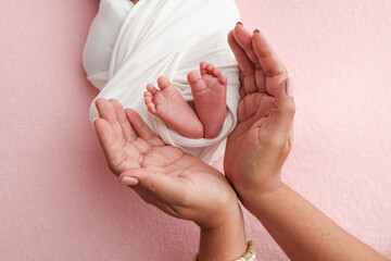 The palms of the parents, father and mother hold the legs, feet of newborn baby