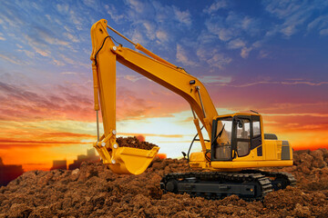 Yellow  Excavators are digging the soil in the construction site on the  sunset  sky background. - obrazy, fototapety, plakaty