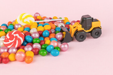 A bulldozer shoveling colorful candies with a bucket.
