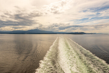 sea mountains and sky: seen from a ferry on the inside passage near bella bella  british columbia with boat wake room for text - obrazy, fototapety, plakaty