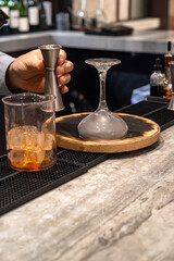 Bartender holding jigger and making smoked whiskey cocktail drink
