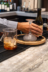 Bartender making smoked whiskey cocktail drink with glass beaker and upside down cocktail glass