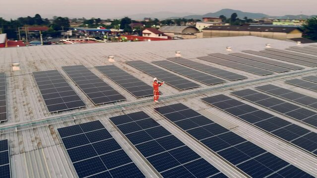 Top view of Engineer man walking and checking solar cell on roof top at industrial factory