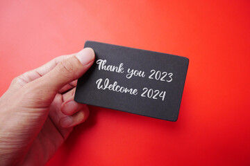 A piece of paper in a man's hand with the words BYE BYE 2023. Goodbye 2023, welcome 2024. Thank you...