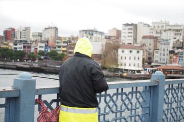 Fisherman with rod, spinning reel on bridge 