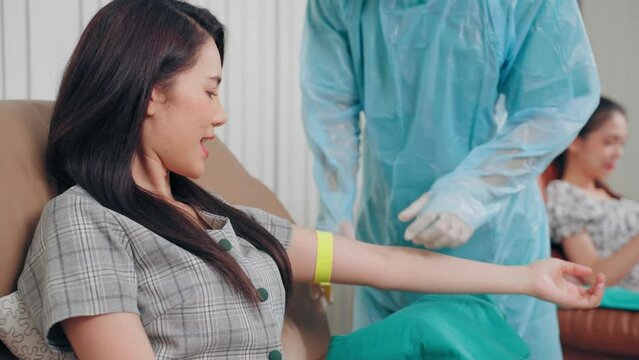 Doctor fumble blood vessel on arm of blood donor asian woman preparing steps during venipuncture to donation at hospital