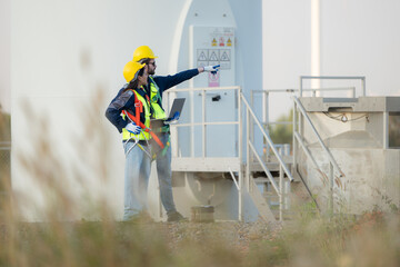 Engineer and worker discussing on a wind turbine farm with laptop - obrazy, fototapety, plakaty