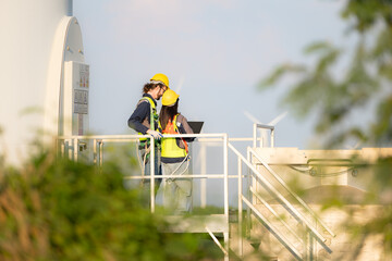 Engineer and worker discussing on a wind turbine farm with laptop