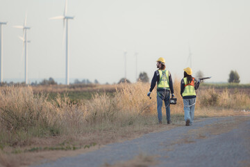 Obraz premium Engineer and worker discussing on a wind turbine farm with laptop