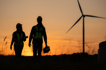 Silhouette of Engineer in charge of wind energy against a background of wind turbines.