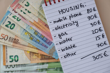 Euro cash money with notebook handwritten housing expenses. Counting bills for electricity, gas, water. Concept of Efficient Consumption and Economy. Spending habits