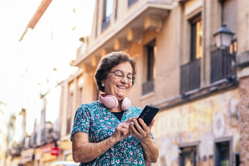 Smiling old woman using smartphone outdoors